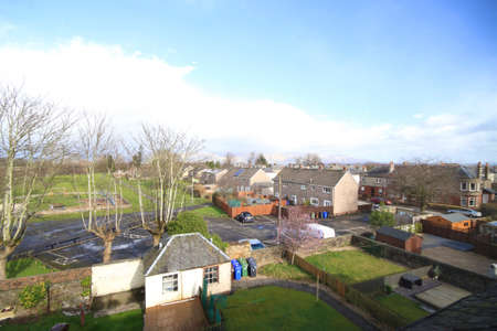 view of the neighbourhood on a sunny day with gardens, houses, trees and cloudy blue skies in view.の写真素材