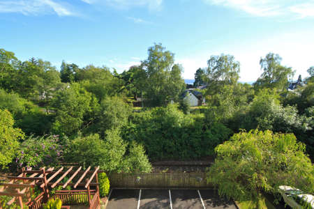 view of residential car park with parking bays, trees and bright cloudy blue skies in viewの写真素材
