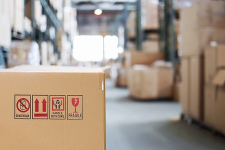 Cardboard box with goods on the background of a blurry modern warehouseの写真素材