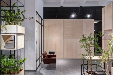 Brown lounge chair in modern loft office on the background of wooden walls