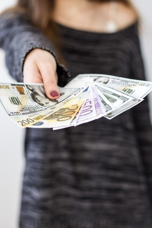 young woman offers money by extending her handの写真素材