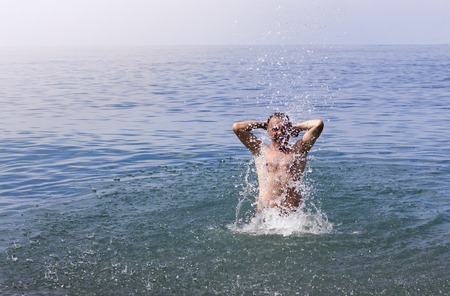 Man rejoices and splashes water in the sea during the summer holidaysの写真素材