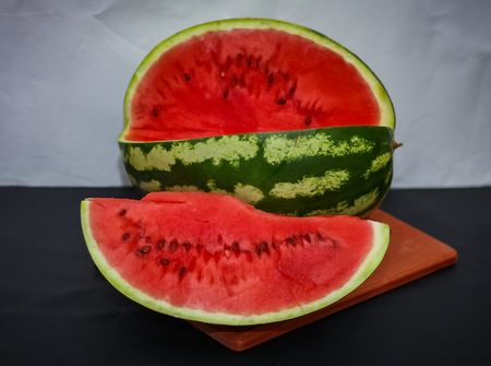 a piece of red juicy watermelon on a watermelon backgroundの写真素材