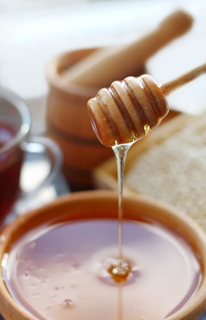 Golden honey in a clay bowl with a wooden spoonの写真素材