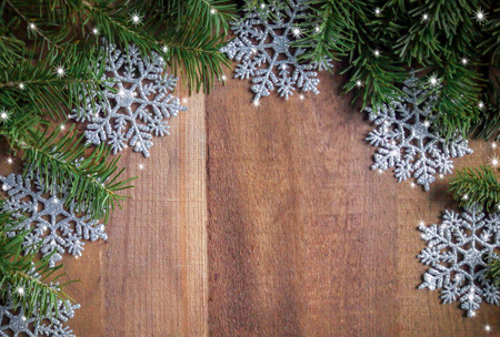background of spruce twigs with snowflakes on wooden surface with copy space