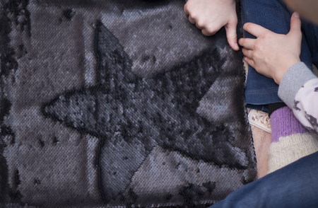 girl draws a star on black fabric with double-sided sequinsの写真素材