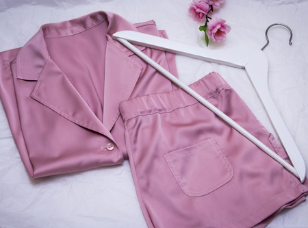 women's silk pink pajamas with hanger and flowers on white backgroundの写真素材