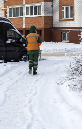 worker carries a shovel for snow removal in winterの写真素材