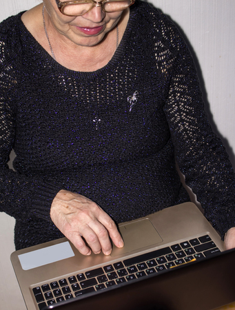 an elderly woman happy to keep the laptop presses the buttonの写真素材