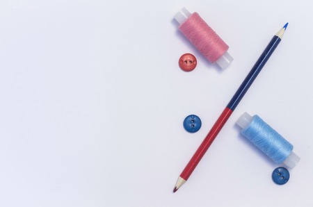 sewing thread with buttons and pencil on the white table of the fashion designer.copy space