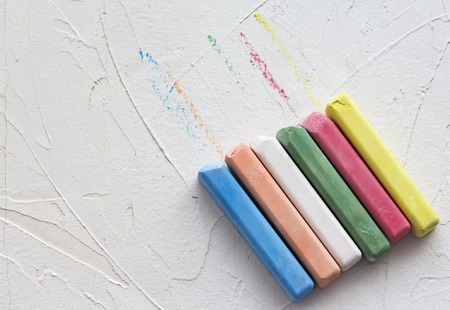 colored crayons lined in a row on a white textured background with a copy of the space.
