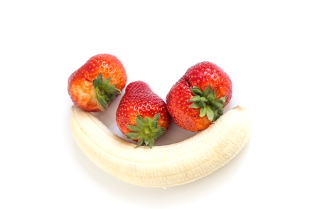 one ripe peeled banana and three ripe strawberries on white background.の写真素材