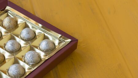 candy in silver wrapper in box on yellow background with copy space.の写真素材