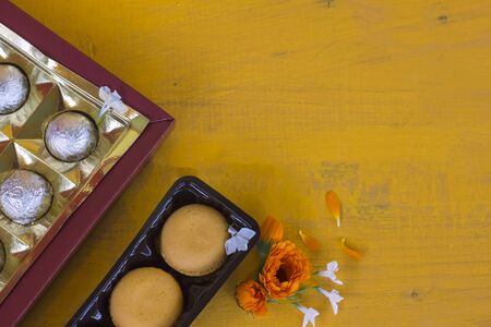 candy in a silver wrapper in a box on a yellow background with a box of macaroons and a copy of the...