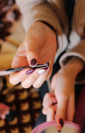 young woman with tweezers and mirror in hand