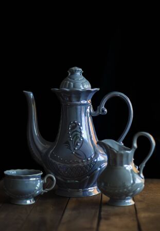 still life with a blue coffee set consisting of a teapot with a milkman and a Cup on a black background .の写真素材