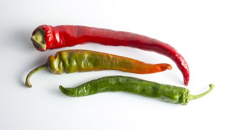 three chili peppers on a white background, ripeness from green to red.
