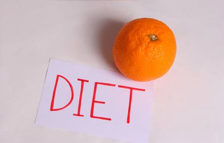 The word diet is written on a white sheet with an orange on a light backgroundの写真素材