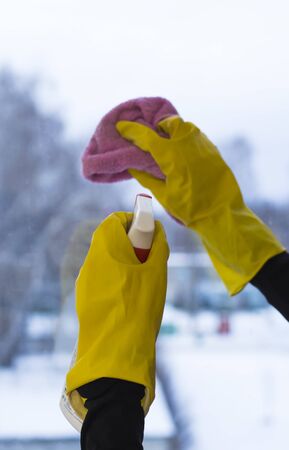The concept of cleaning housing, a woman in yellow gloves washes the window with a special tool.の写真素材