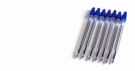 lots of transparent ballpoint pens with a blue cap on a white background