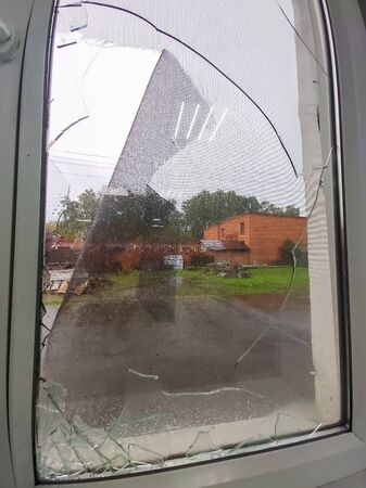 the storm left a broken window with shards of glass.
