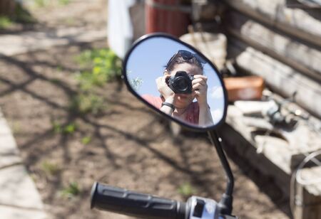 a photographer with a camera is displayed in the mirror of the scooter.の写真素材