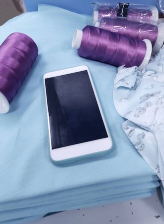 manufacture of wearing apparel , a smart phone with Internet to help work on the production,concept of production and technology.の写真素材