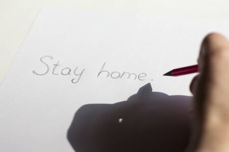 Stay at home, writes a hand in a notebook in bright sunlight, quarantine the epidemic of the disease coronavirusの写真素材