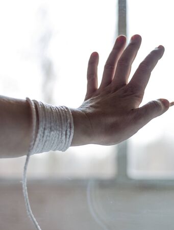 a womans hand with a rope that prevents a person from going outsideの写真素材