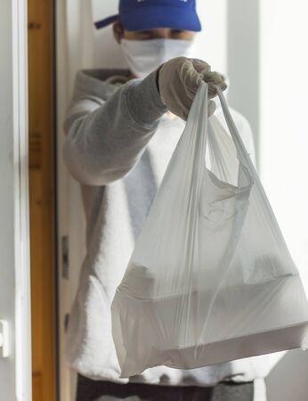 A young man with a bag of food for the elderly during the crown virus pandemic.の写真素材