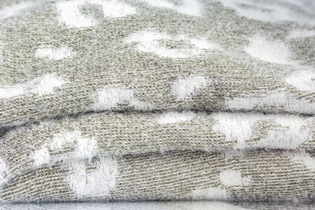 a stack of grey knitwear with a white pattern as the background.