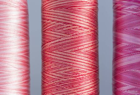 Colored silk melange threads of red hue on bobbins close up.の写真素材