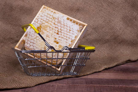 honeycomb in an iron basket on a wooden table on a background of burlapの写真素材