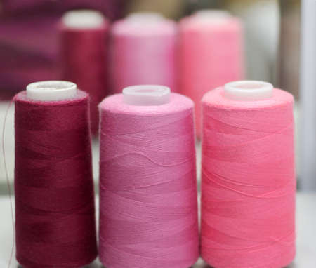 sewing threads in pink shades stand in a row against the background of the mirror in the Studio.の写真素材
