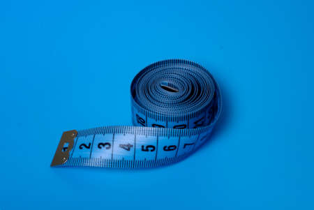 Close-up view of a blue measuring tape on a blue backgroundの写真素材