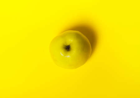 Yellow Apple on a yellow background, top view, minimal concept.の写真素材