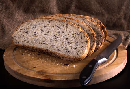 slices of sliced bread and a knife, still life on a rustic background.
