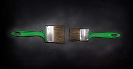 flat lay horizontal, two green brushes one black textured background with a vignette.