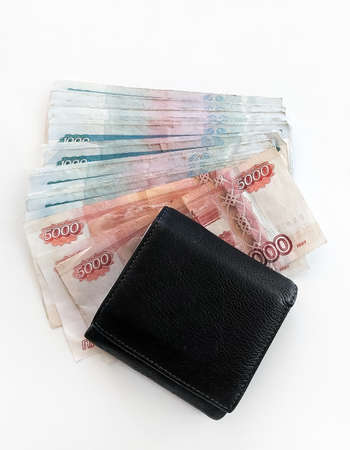 Russian rubles of categories one thousand and five thousand with a black wallet on them on a white background, top View.の写真素材