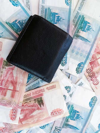 Russian rubles of categories one thousand and five thousand with a closed wallet on them, top View.の写真素材