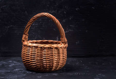 wicker wooden basket on a black abstract background with a copy of the space.の写真素材