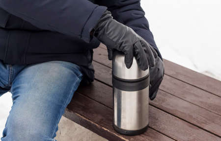 a man opens a hot coffee in winter to keep warm.