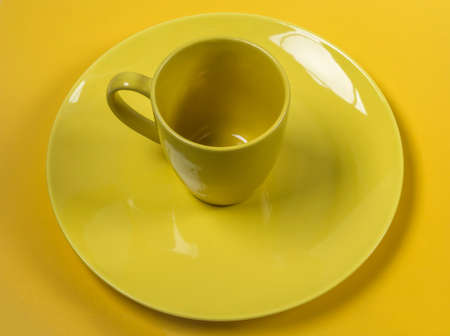 empty yellow plate and cup on a yellow background top viewの写真素材
