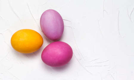 Easter bright eggs lay flat on a white textured background with a copy of the space.の写真素材