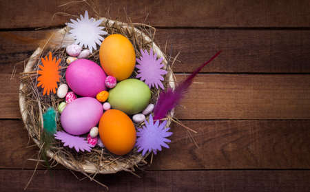 beautiful Easter eggs with ornaments in a plate on a rustic background lay flat, with a copy of the...