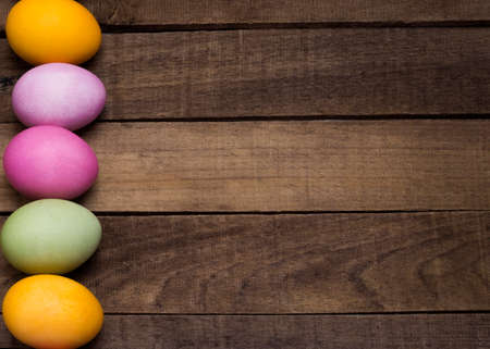 bright Easter eggs on the background of a wooden table with a copy of the space.の写真素材