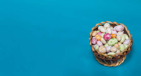 Colorful round candies in a basket, on a blue background