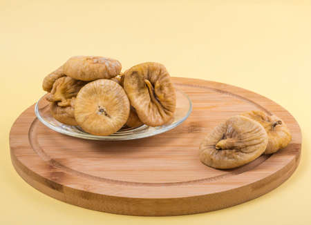 dried figs in a glass plate on a yellow background.の写真素材