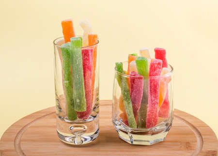 oriental sweets candied pineapple in two glasses on a yellow background.
