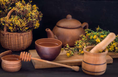 a cup of herbal tea on a board on a wooden table made of St. John's wort grass.の写真素材